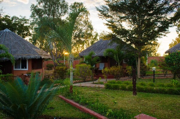 A resort with thatched-roof huts, a well-maintained garden, and a pathway leading to the buildings. - Edena Kely (Mahajanga)