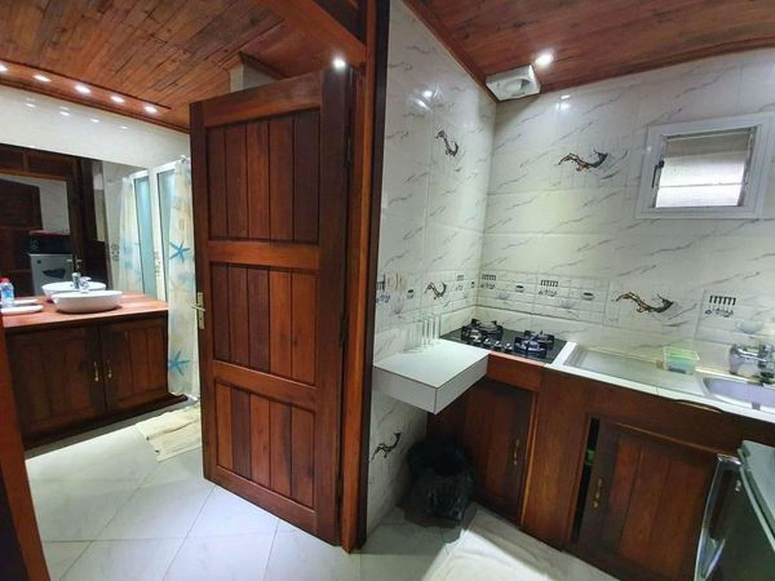 Cocina con armarios de madera, encimera blanca y salpicadero de azulejos.