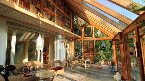 A spacious room with a high ceiling, wooden bookshelves, and a large window allowing natural light. - Landhaus Lichthof (Lohmar)