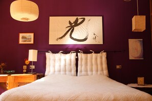 A bed with white bedding, a large framed calligraphy piece on the wall, and a hanging light fixture. - B&B Ca' Dell'Olmo (Pesaro)