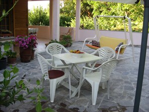 A patio with white plastic chairs and a table, surrounded by potted plants and a swing chair. - B&B Ca' Dell'Olmo (Pesaro)