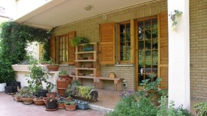 Een overdekt terras met plantenpotten en een bakstenen muur.