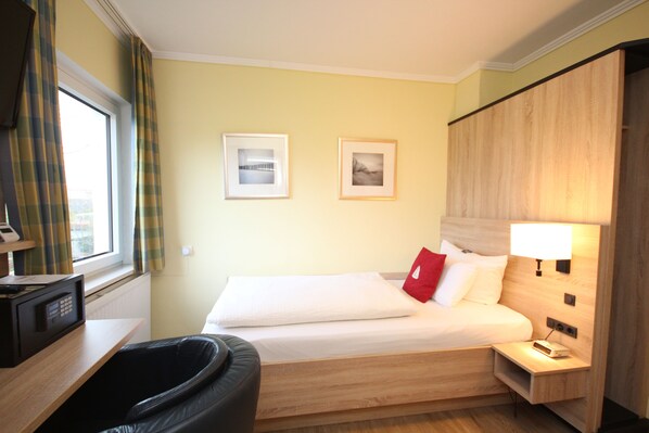 Una habitación de hotel con una cama, mesita de noche, lámpara y microondas en una encimera.