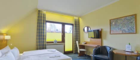 A hotel room with a bed, a desk, a chair, a television, and a painting on the wall.