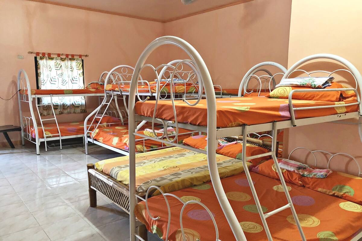 A dormitory room with bunk beds, a whiteboard, and a window with curtains.