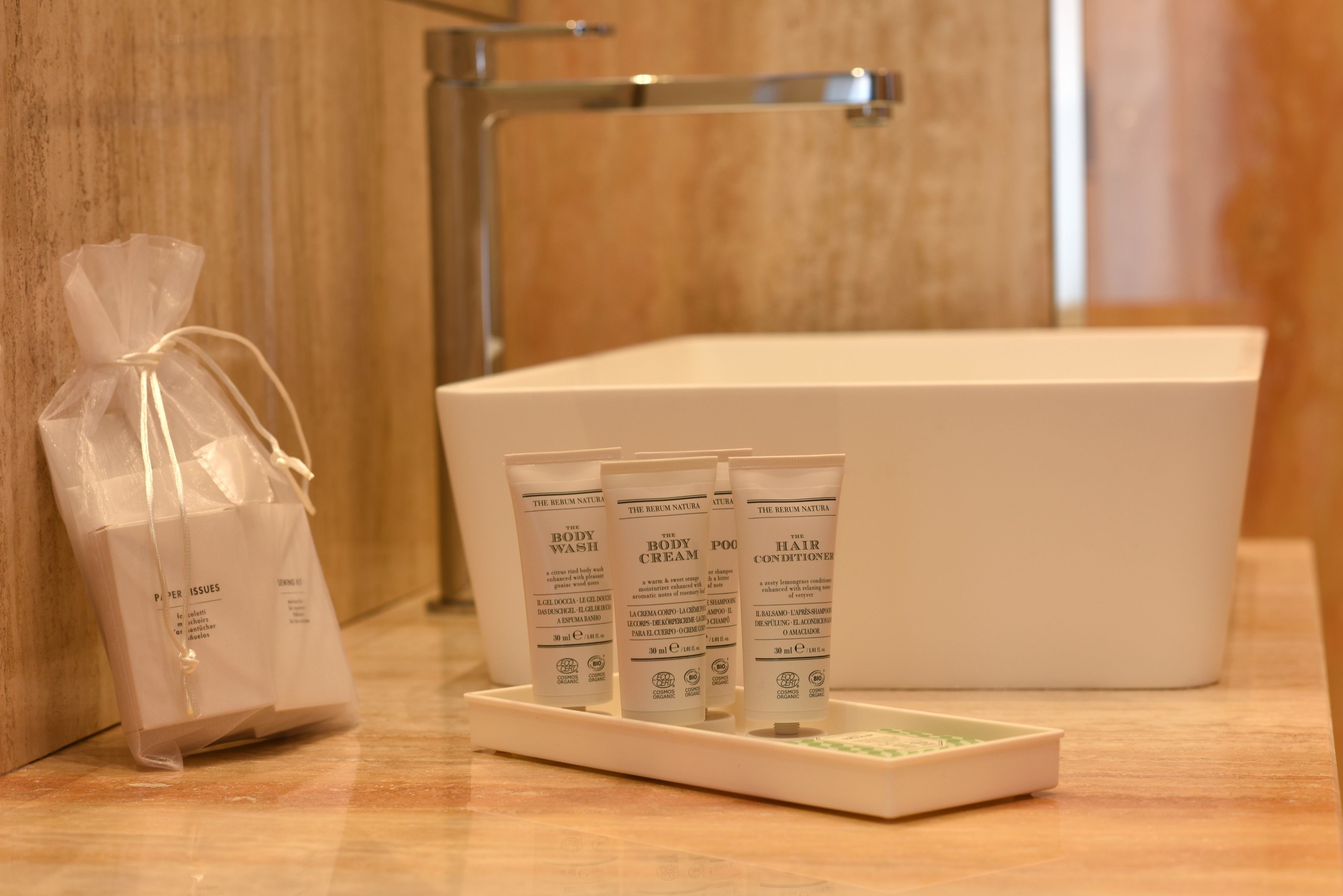 Un bagno con una vasca da bagno bianca, articoli da toilette tra cui bagnoshampoo e balsamo, e una piccola busta regalo.