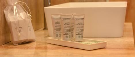 Un bagno con una vasca da bagno bianca, articoli da toilette tra cui bagnoshampoo e balsamo, e una piccola busta regalo.