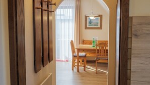 A hallway leading to a dining area with wooden furniture and a painting on the wall. - Appartementhaus Alt Büsum (Büsum)