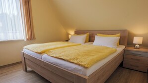 A single bed with a wooden frame, a bedside table with a lamp, and a window with curtains. - Appartementhaus Alt Büsum (Büsum)