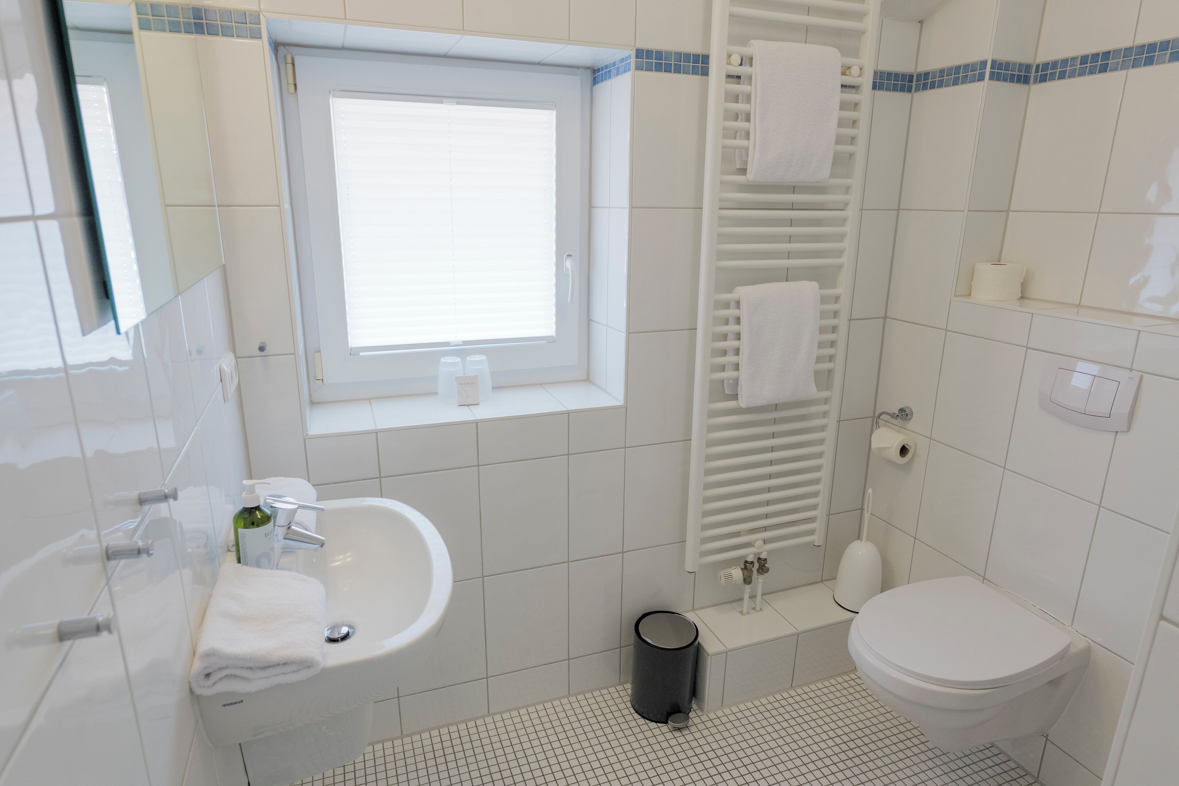Un baño moderno con lavamanos, inodoro y ventana.