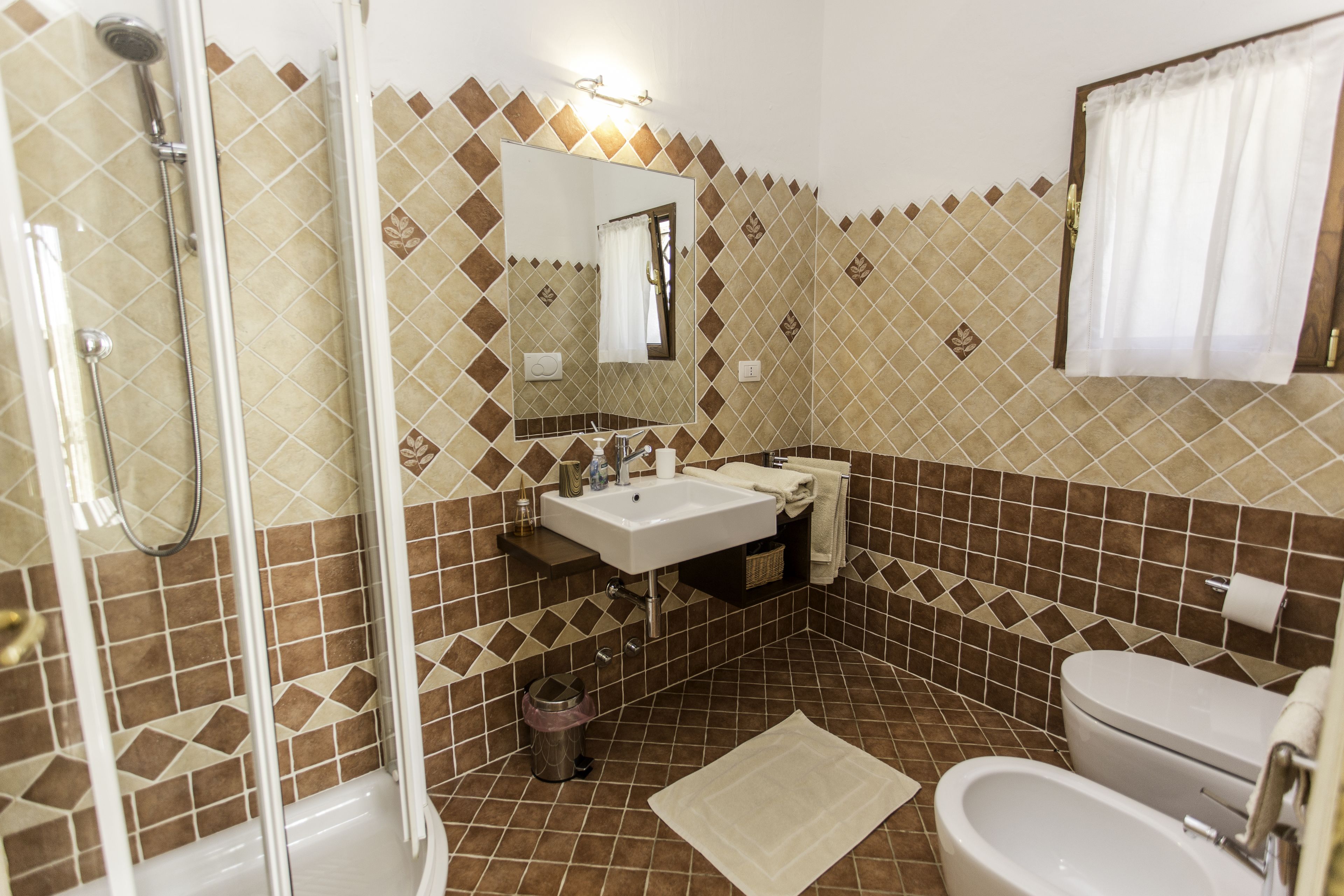 A bathroom with a shower, sink, toilet, and bidet.