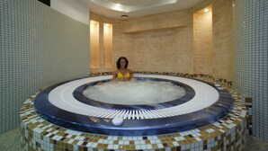A hot tub with a tiled interior and a person sitting inside. - Hotel Gold (Swinoujscie)