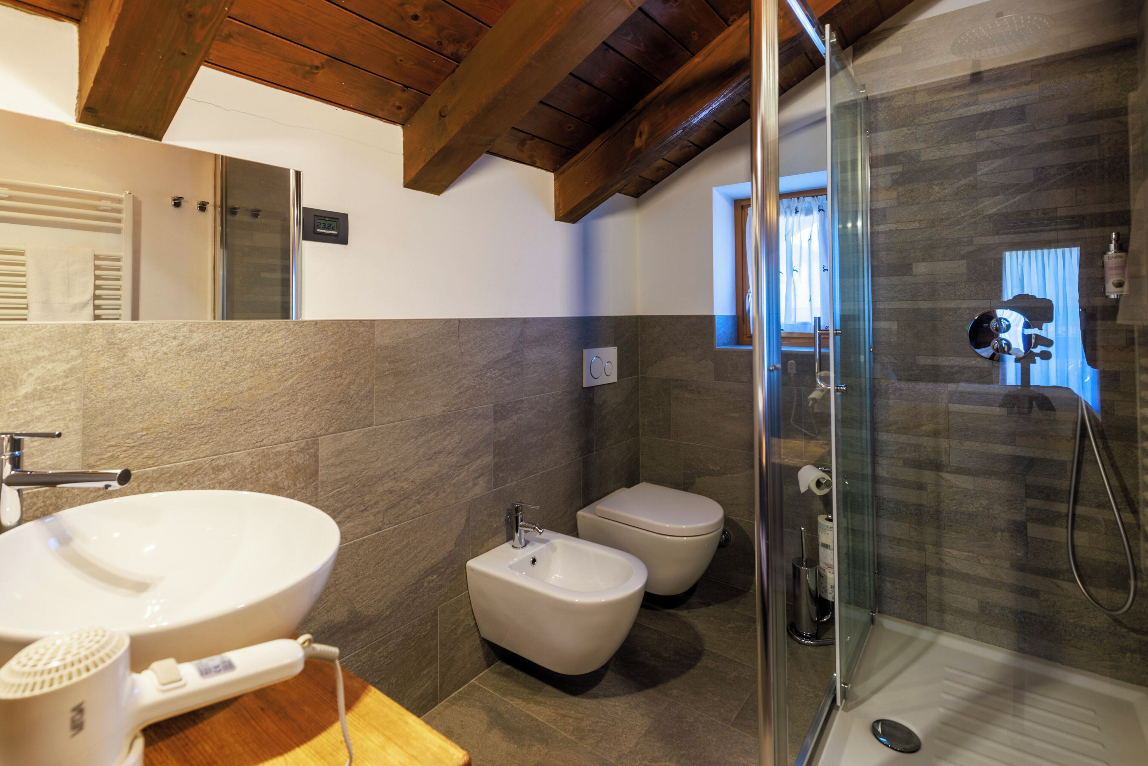 Une salle de bain moderne dotée d’un grand lavabo, d’un bidet et d’une douche à parois de verre.