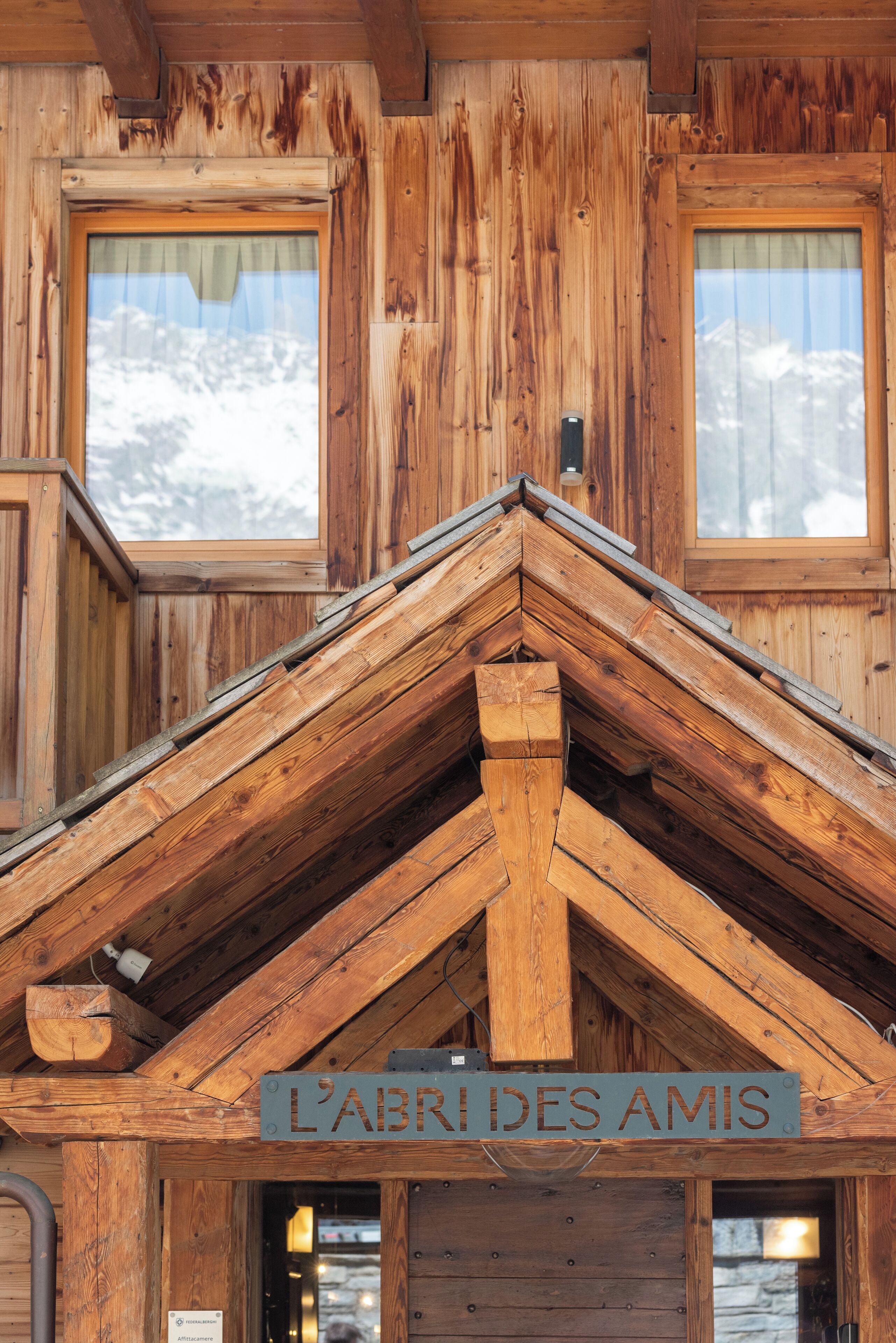 Un edificio de madera con un letrero que dice 'L'ABRIDES AMIS' y una ventana con vista a la nieve.