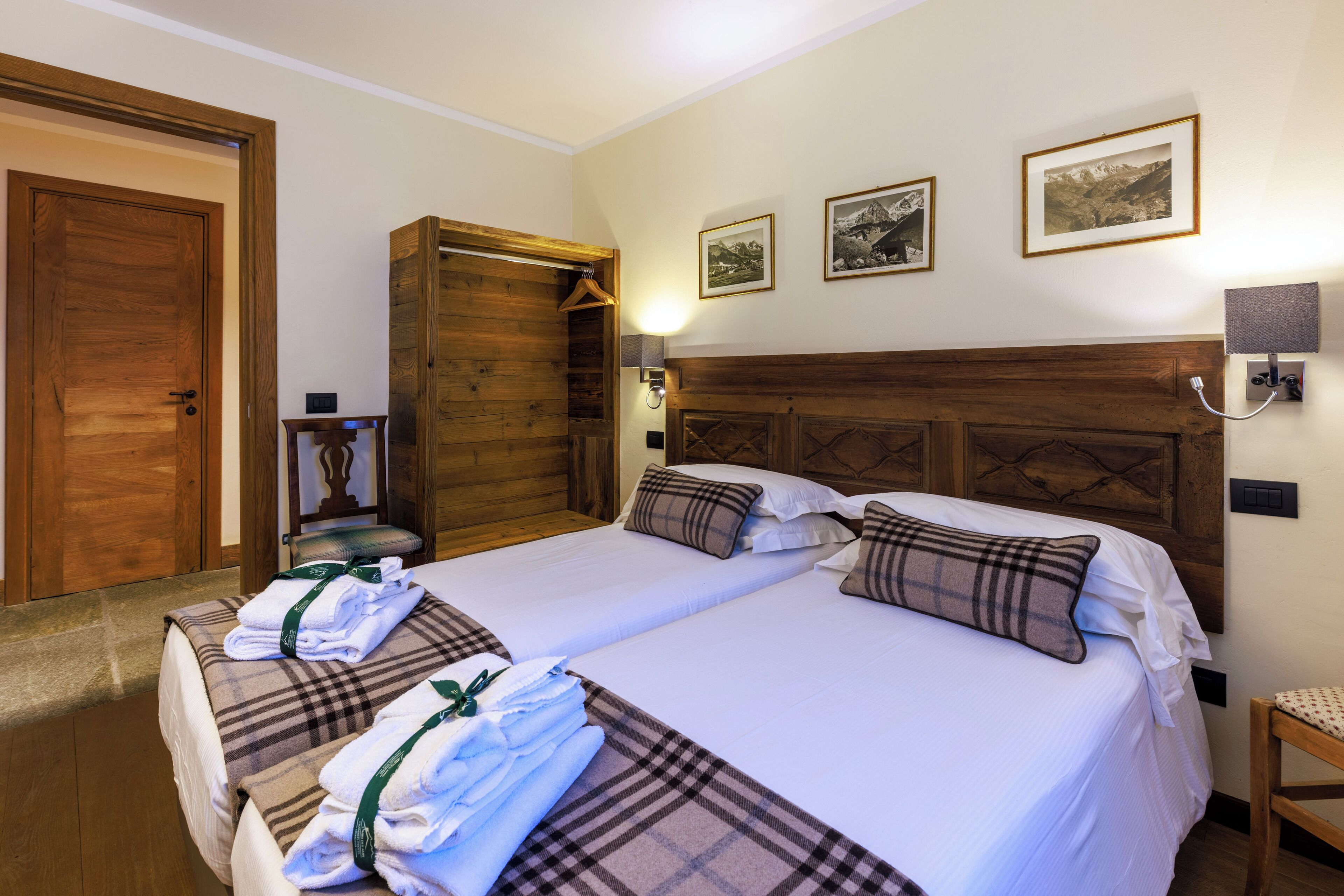 A hotel room with two beds, wooden headboards, and a wardrobe.