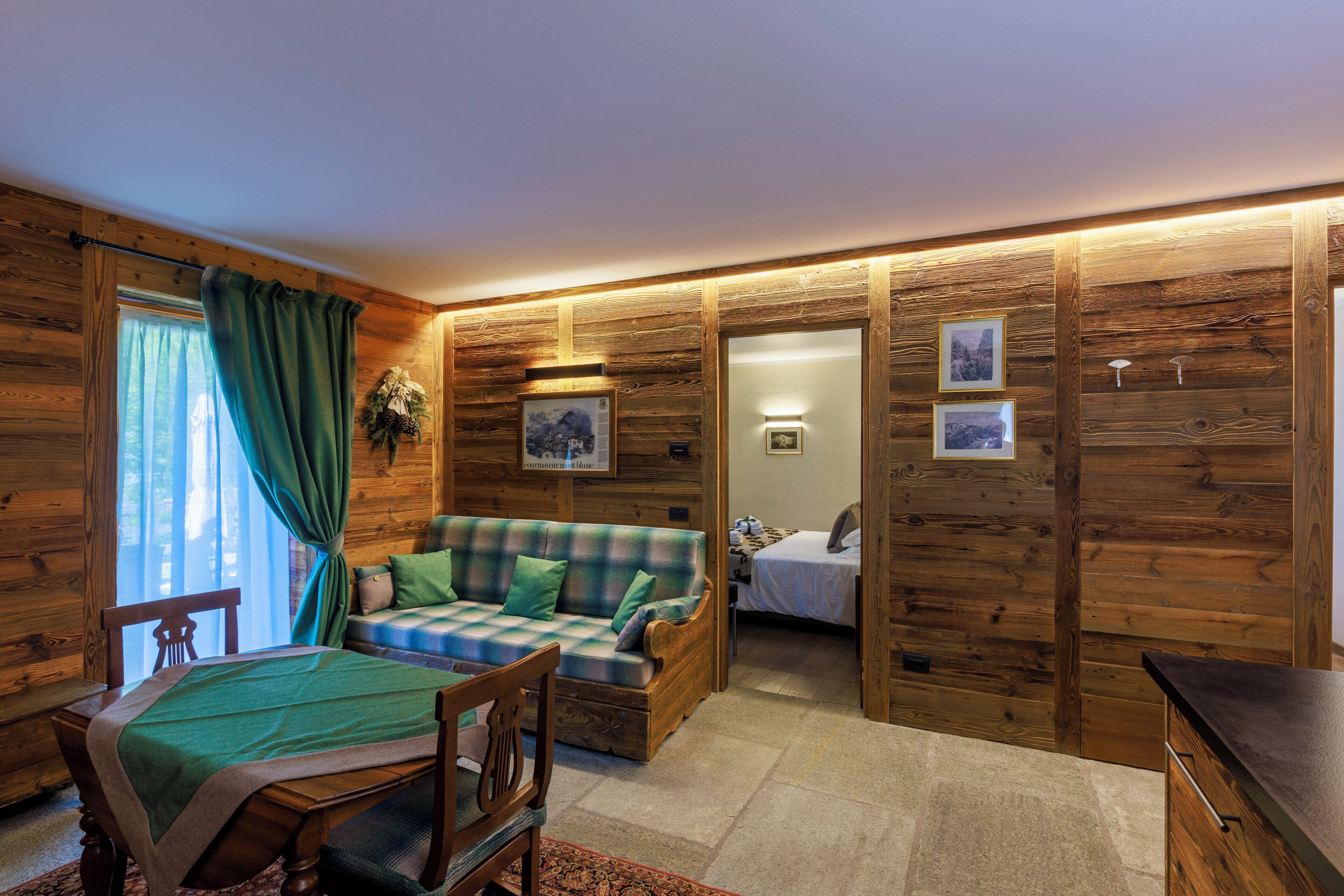 A cozy room with a wooden interior, a bed, a sofa, and a dining area.