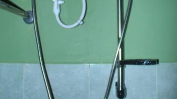 A shower setup with a handheld showerhead and a wall-mounted control panel.