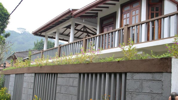 A traditional building with a balcony, a stone wall, and a mountainous backdrop. - Selfcate Luxury Apartments (Kandy)