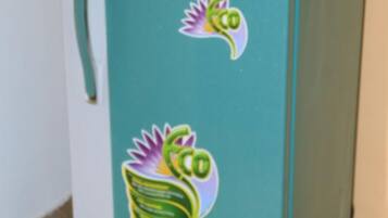 Un refrigerador color turquesa con un asa en el lado izquierdo y un adhesivo de una planta en la parte frontal.