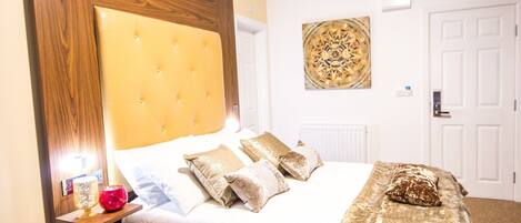 A neatly made bed with a tufted headboard, a bedside table with a lamp, and a decorative wall piece.