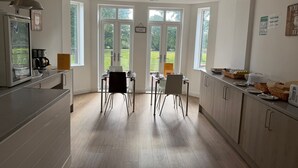 A modern kitchen with large windows, a coffee machine, and a dining area with two chairs. - Trivelles Gatwick (Crawley)