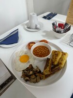 Un plato de desayuno con huevo frito, frijoles, champiñones y tostadas.