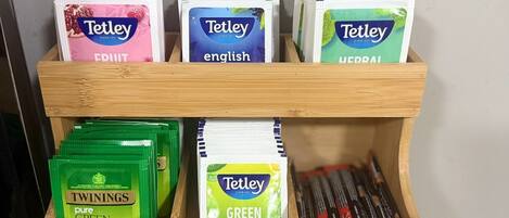 Exposição de madeira com diversos saquinhos de chá Tetley, incluindo chás English, Uddai e Twinings green tea.