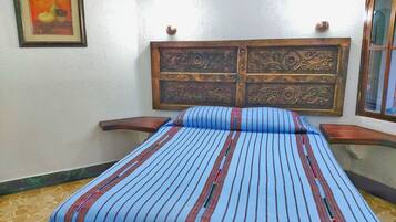 A room with a bed, a framed picture on the wall, and a decorative headboard.