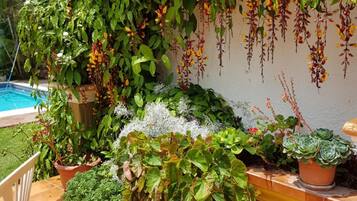 A patio with a tiled floor, potted plants, and a white chair.