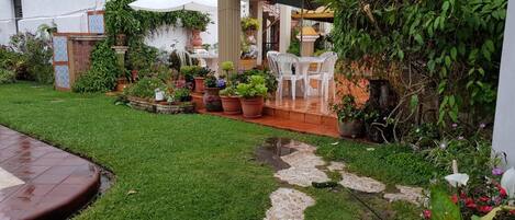 A well-maintained garden with a patio area, potted plants, and outdoor furniture.