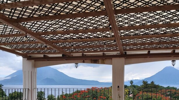 A covered outdoor area with a view of a mountain and a body of water. - Perla Maya Hotel (Panajachel)