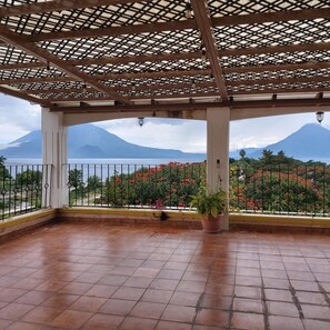 A covered outdoor area with a view of a mountain and a body of water. - Perla Maya Hotel (Panajachel)