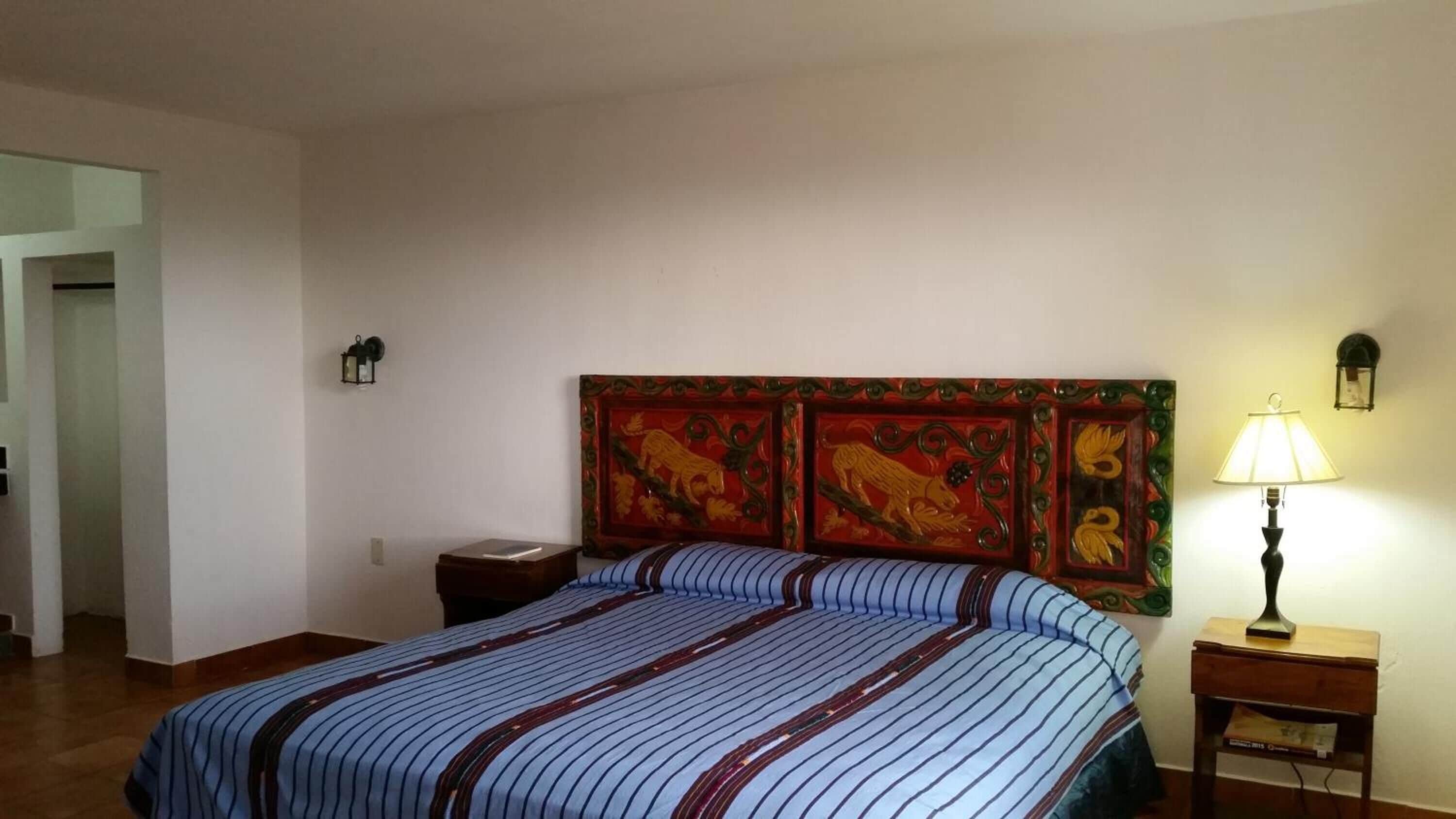 Ein Hotelzimmer mit einem Bett, einem Nachttisch mit Lampe und einem dekorativen Kopfteil.