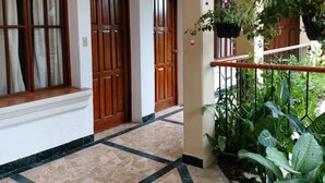 A corridor with tiled flooring, wooden doors, and hanging plants. - Perla Maya Hotel (Panajachel)