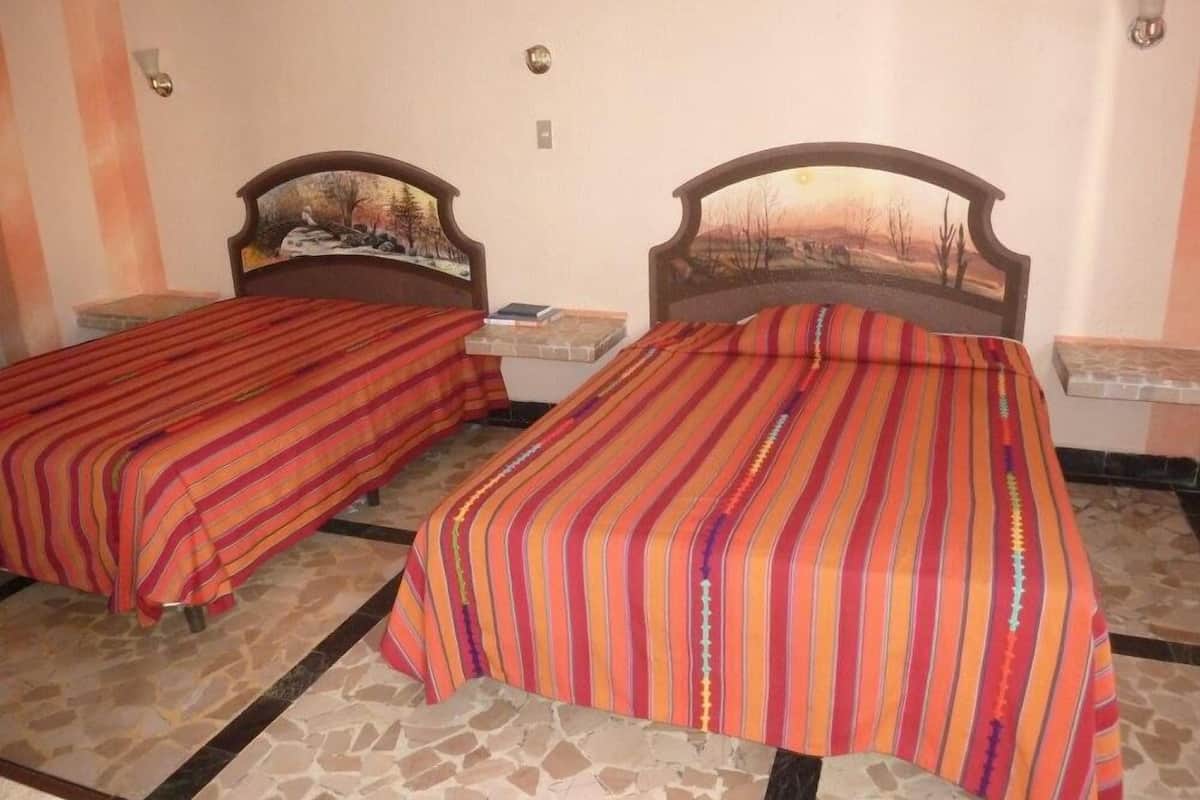 A room with two beds, each with a headboard and a nightstand. The beds have striped bedding.