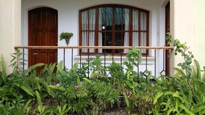 A building with a balcony, a wooden door, and a window with curtains. - Perla Maya Hotel (Panajachel)