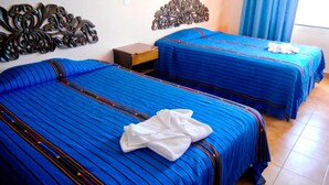 A hotel room with two beds, each with blue bedding and decorative headboards. - Perla Maya Hotel (Panajachel)