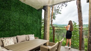 A wooden deck with a dining table and wicker chairs, overlooking a lush green landscape. - Hotel Elbrus SPA & Wellness (Velingrad)