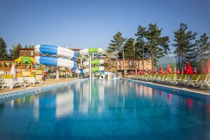 Une piscine avec des toboggans et des chaises longues.
