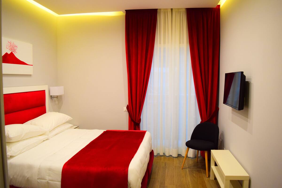 Ein Hotelzimmer mit Bett, Fernseher, Stuhl und einem kleinen Tisch.