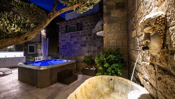 A stone building with a hot tub, a stone fountain, and a statue.