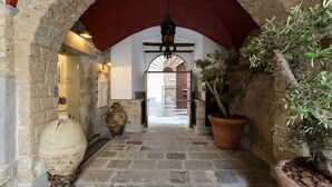 A stone corridor with an arched ceiling, a large vase, and potted plants. - Antica Dimora Magi (Sorrento)