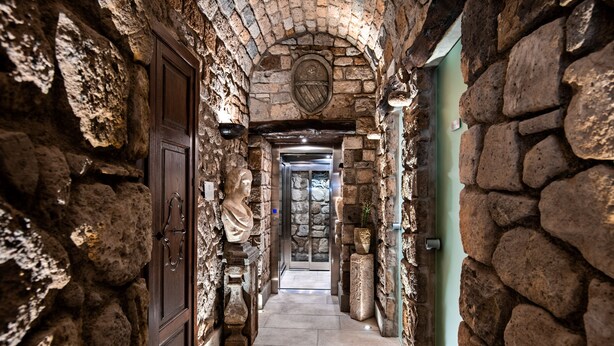 A stone corridor with a statue, a coat of arms, and a door. - Antica Dimora Magi (Sorrento)