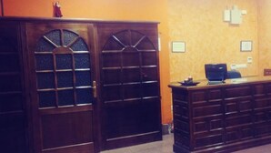 Een receptie met een houten toonbank, een computer en ingelijste certificaten aan de muur.