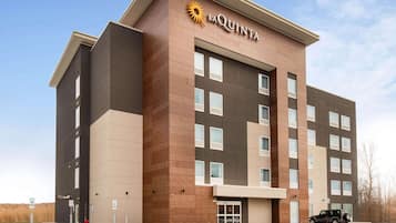 Um hotel La Quinta com design moderno, exibindo uma logo marcante, vários andares e uma área de estacionamento.