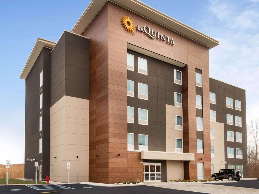 Um hotel La Quinta com design moderno, exibindo uma logo marcante, vários andares e uma área de estacionamento.