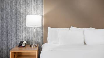 A hotel room with a bed, a bedside table with a lamp, and a telephone.