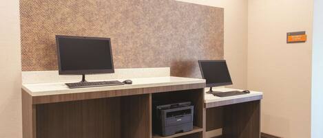 A reception desk with two computer stations, a printer, and a sign indicating the business center.