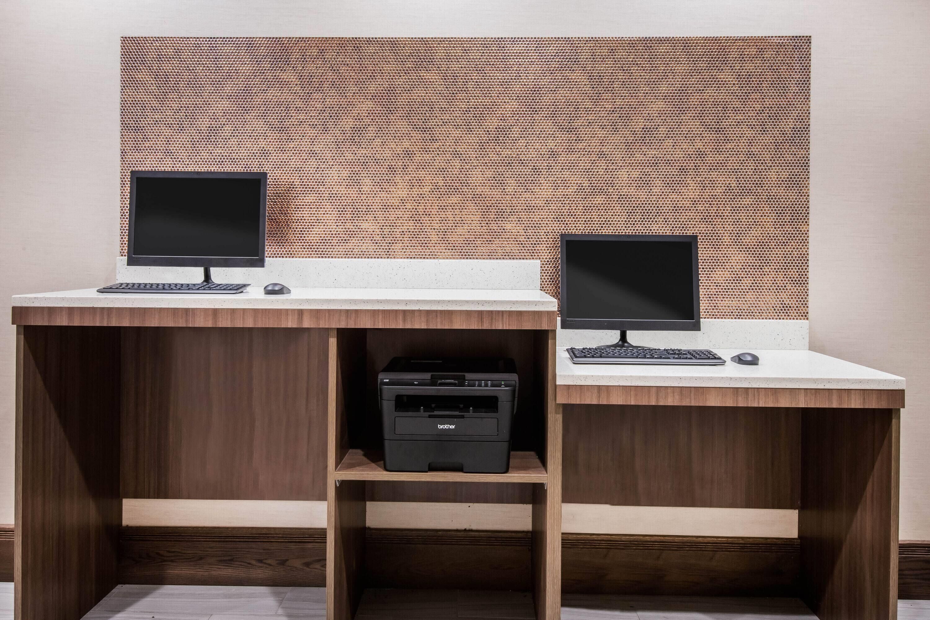 A modern office desk with two monitors, a keyboard, and a printer.