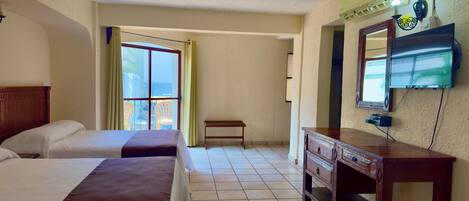 A hotel room with two beds, a wooden dresser, a bench, and a television mounted on the wall.
